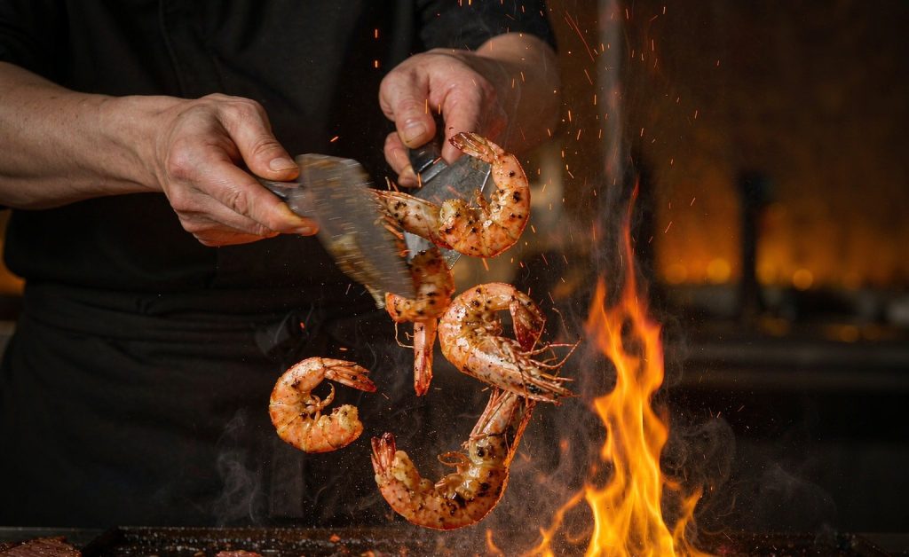 Teppanyaki chef tossing shrimp and steak on a hibachi flat-top grill at a home party in Carlsbad, San Diego County